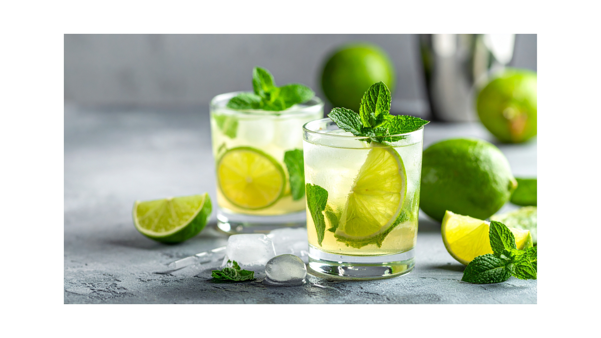 Tumbler glasses are shown filled with a lime based cocktail, sprigs of mint poke out of the top of the glasses.